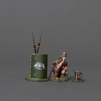 Image of Roman Soldier Cooking--crouching figure and 19th Legion green shield with two leaning spears and cooking stove with frying pan #52087