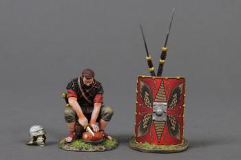The Meat Cutter (A)--single Roman Legionary figure in Red tunic sitting on a bucket cutting meat, helmet, and two pila leaning on red shield #53060