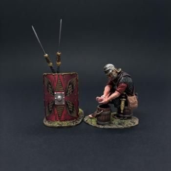 The Washerman with Red Shield (A)--single Roman Legionary figure seated on bucket & washing clothes and shield leaning on two spears  #53375